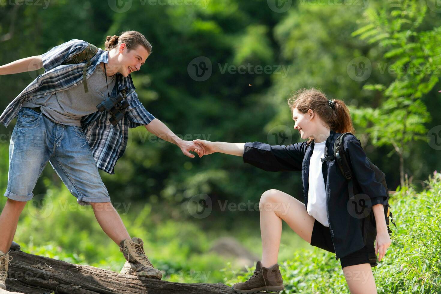 Young couple hiking in the forest with backpacks and trekking poles photo