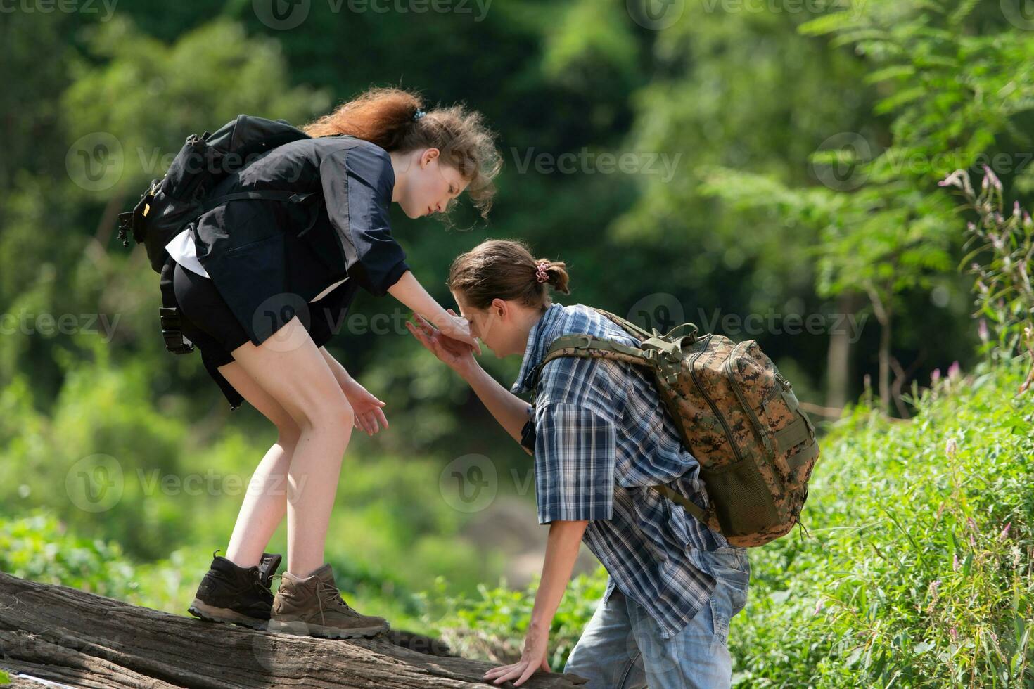 Young couple hiking in the forest with backpacks and trekking poles photo