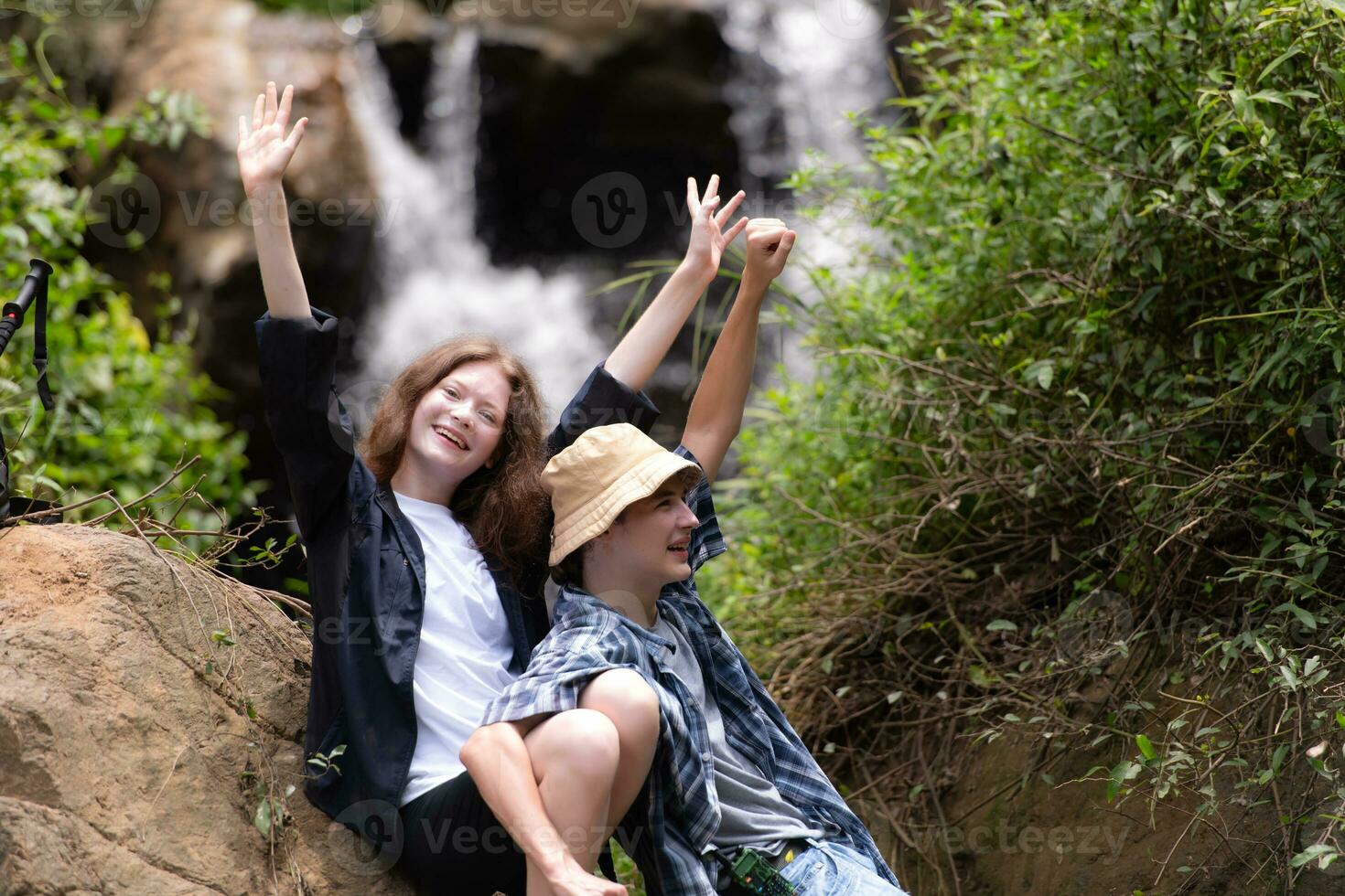 Young couple of hikers sitting on a rock and kissing photo