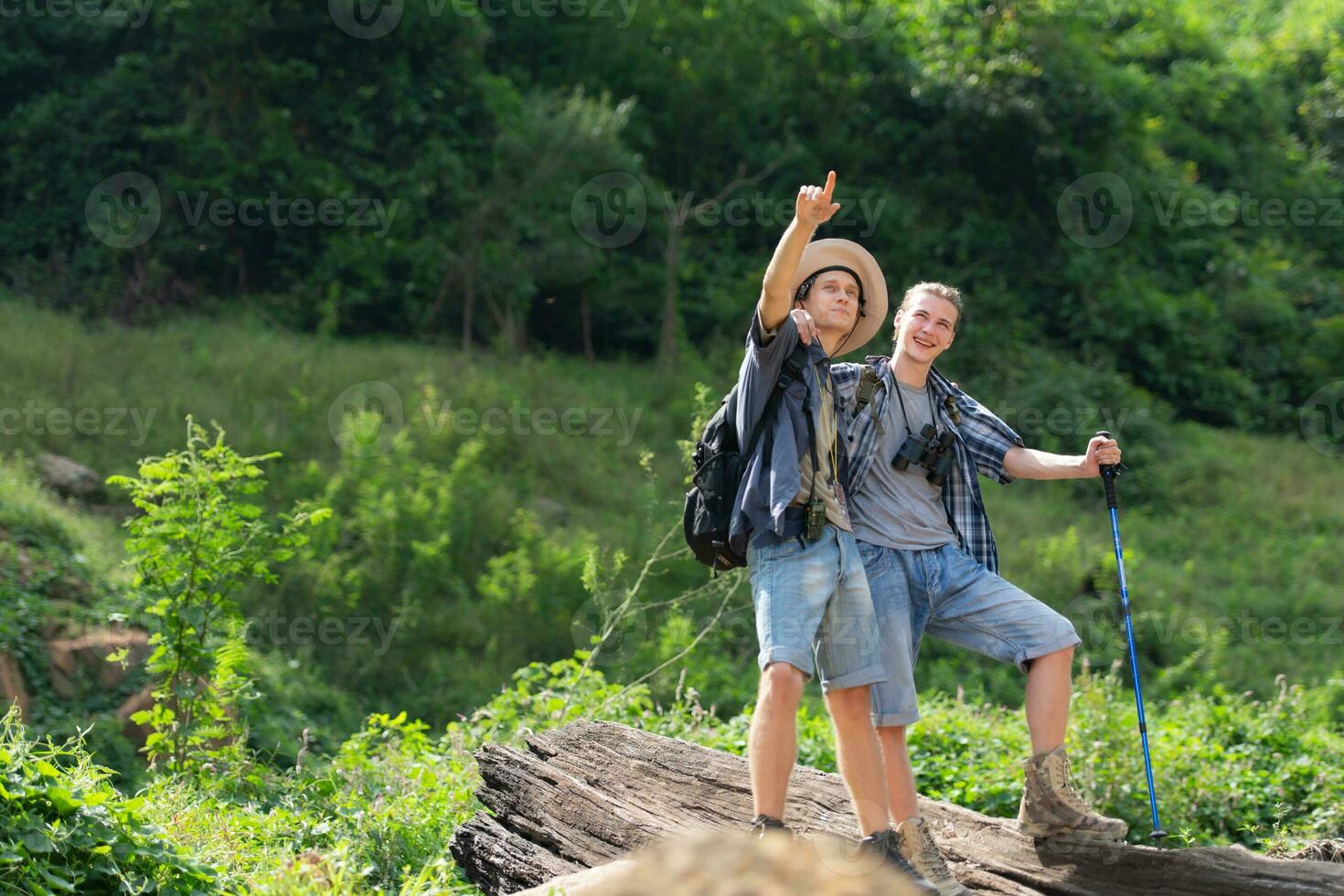 Two man hiking in the forest with backpacks and trekking poles photo