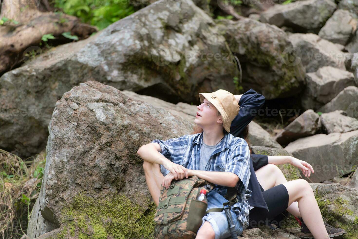 Young couple hiking in the forest with backpacks and trekking poles photo