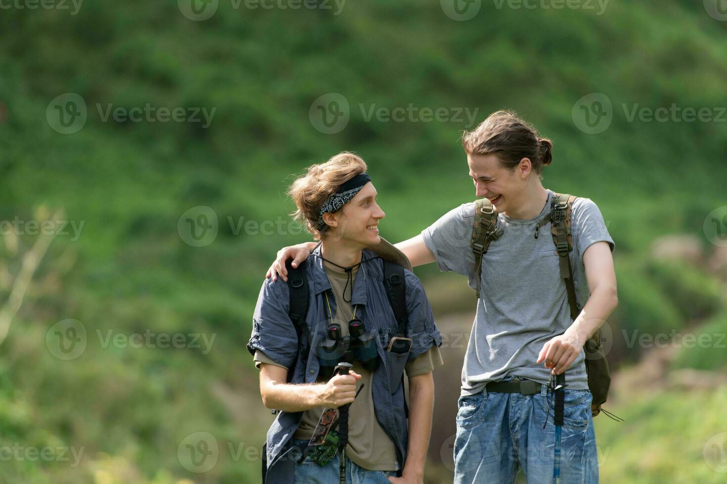 Two man hiking in the forest with backpacks and trekking poles photo