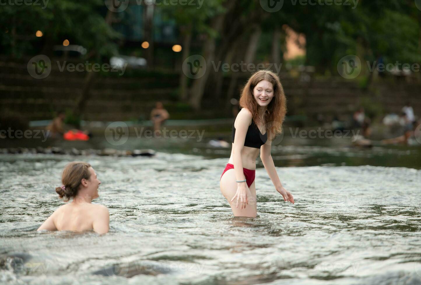 Young couple having fun in the water of a river on a hot summer day photo