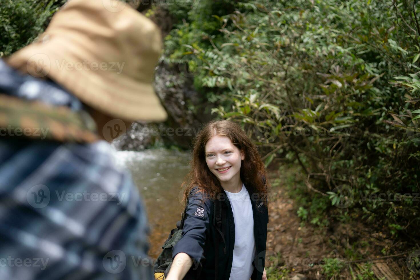 Young couple of hikers sitting on a rock and looking at each other photo