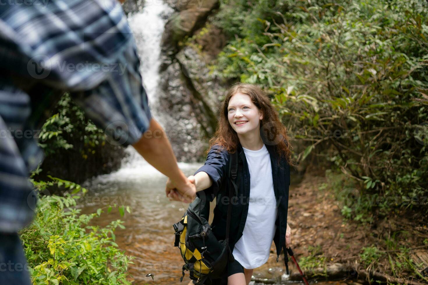 Young couple of hikers sitting on a rock and looking at each other photo