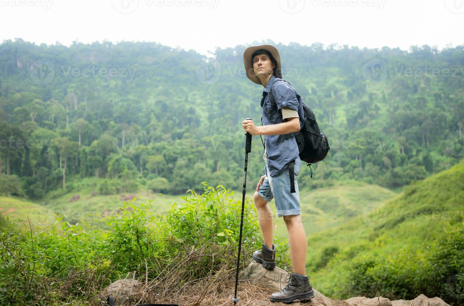 Young man with backpack hiking in the forest. Active lifestyle concept. photo