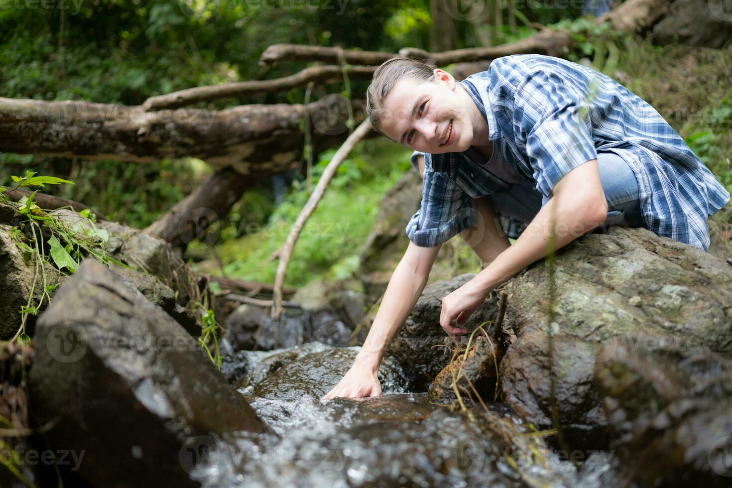 Hiker in the jungle playing with water in a stream in the forest. photo