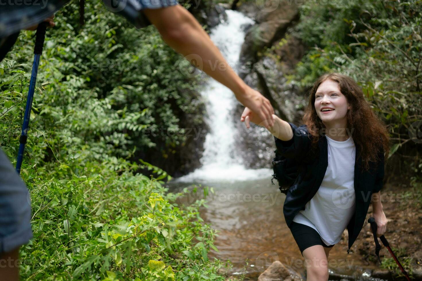 Young couple of hikers sitting on a rock and looking at each other photo