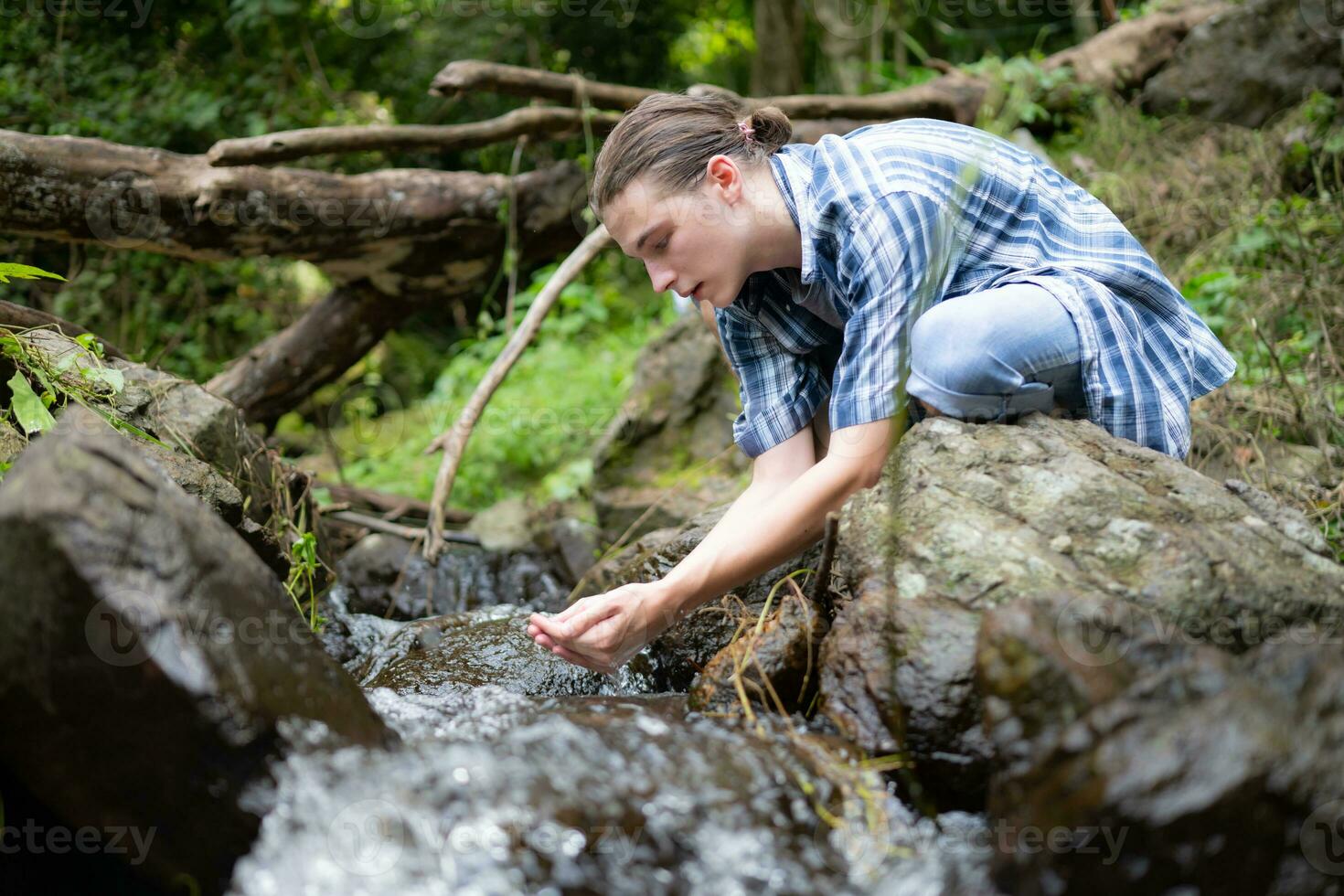 Hiker in the jungle playing with water in a stream in the forest. photo