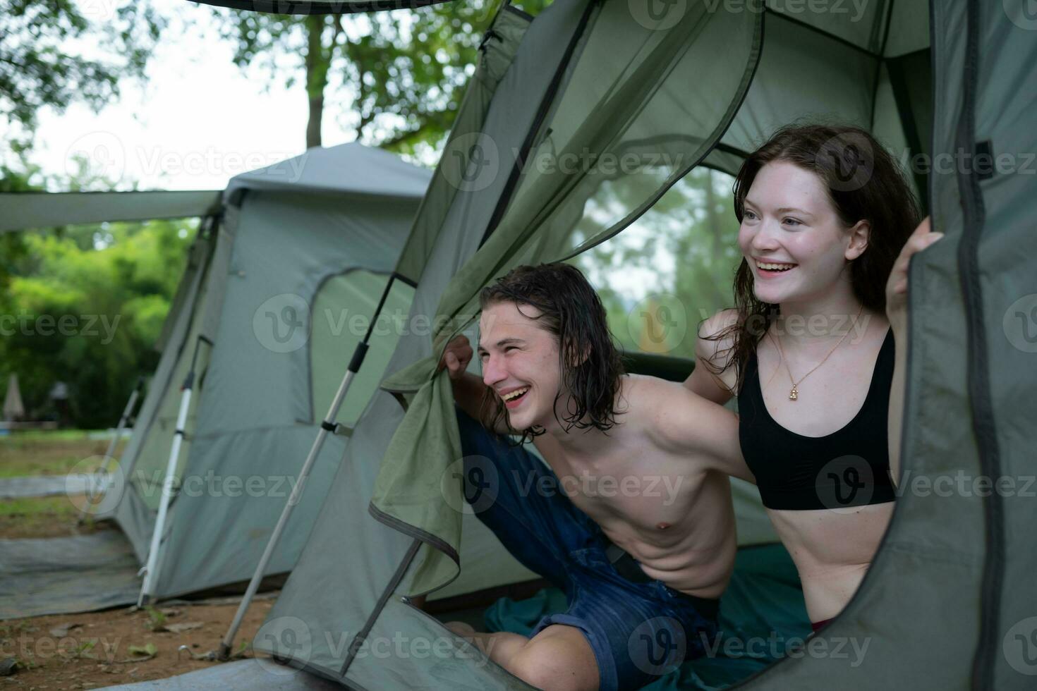 Young couple camping in tent in forest smiling happy and relaxed looking at camera photo