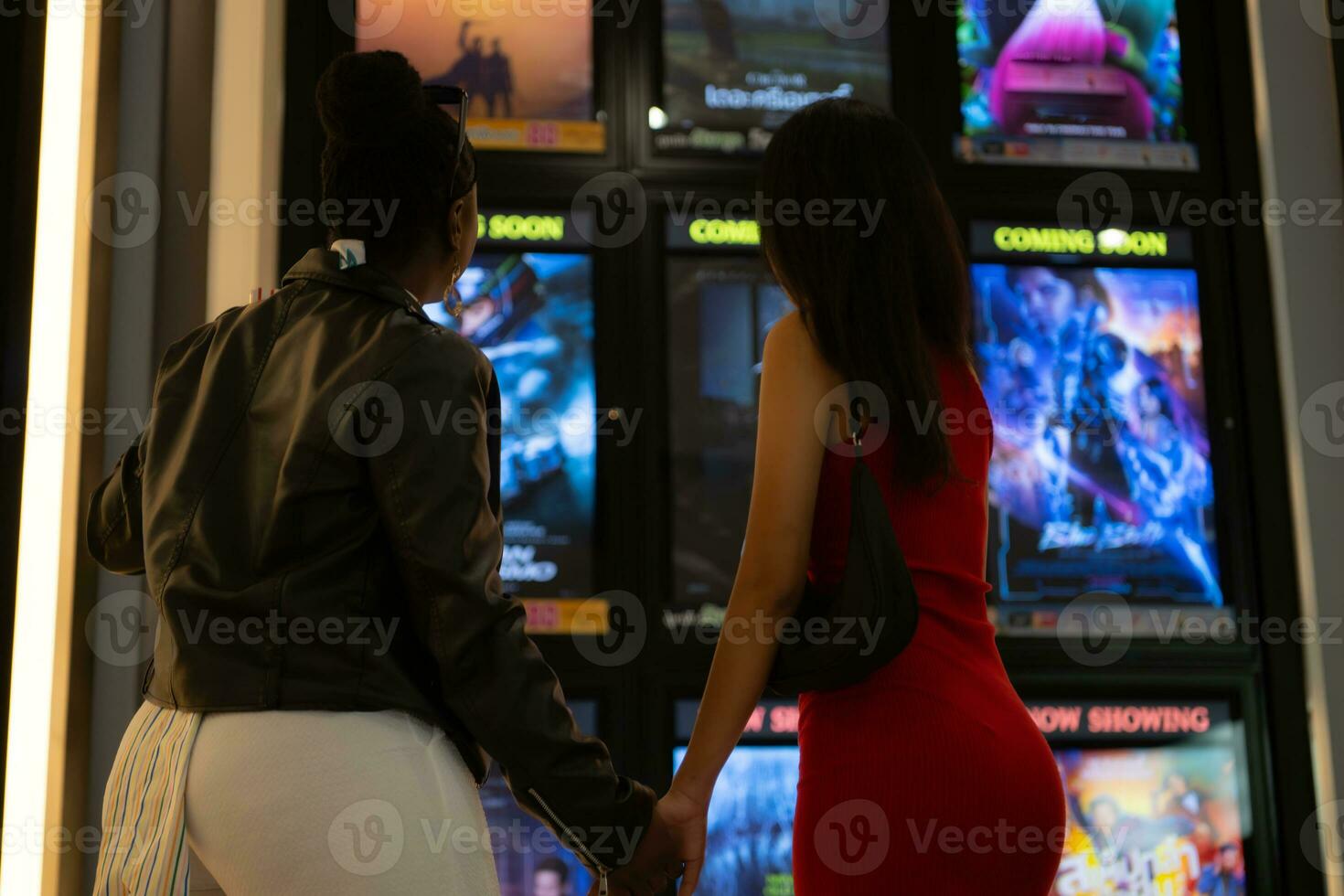 Both of young woman stand and watch the movie program to watch today. photo