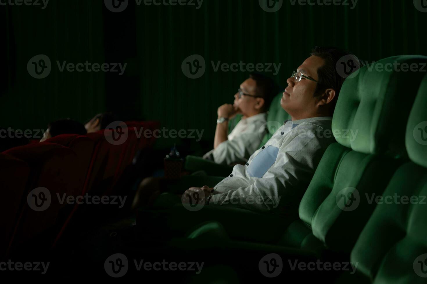 Young couple watching movie in cinema, sitting on the green seats. photo