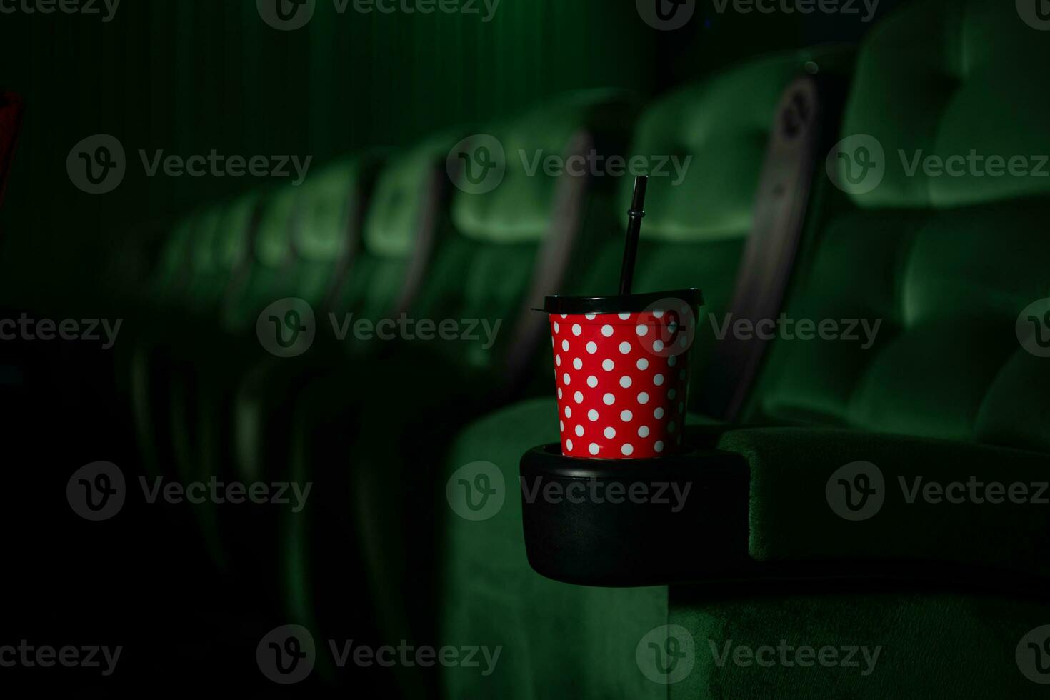 Cinema auditorium with green seats and a red cup of drink photo