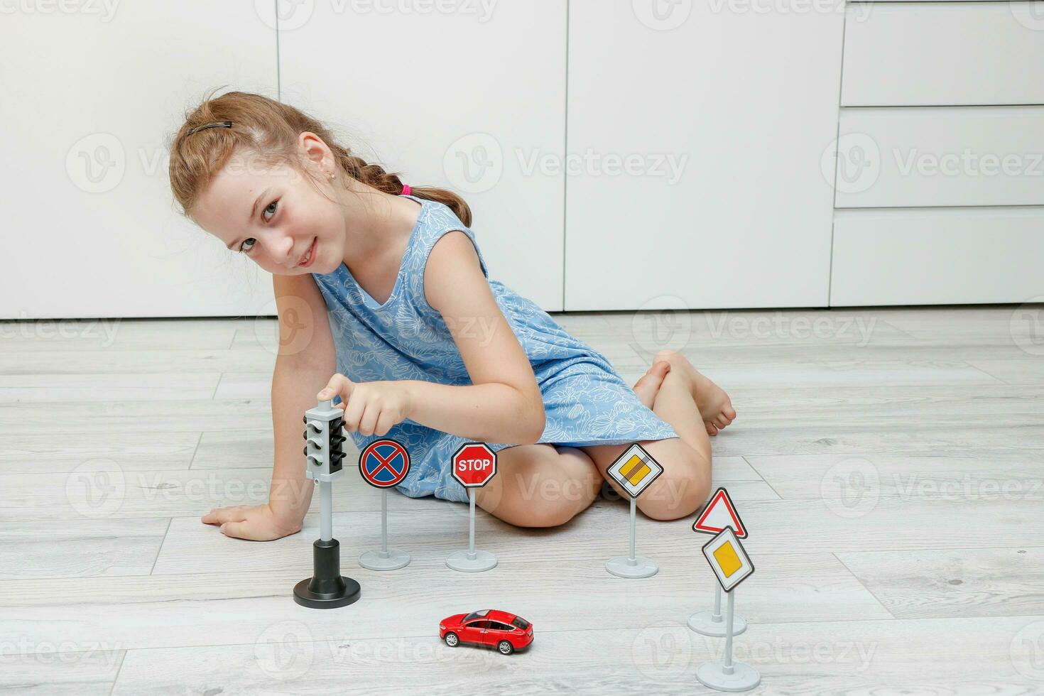 cute little girl playing at home on the floor with a typewriter, road signs and traffic lights photo