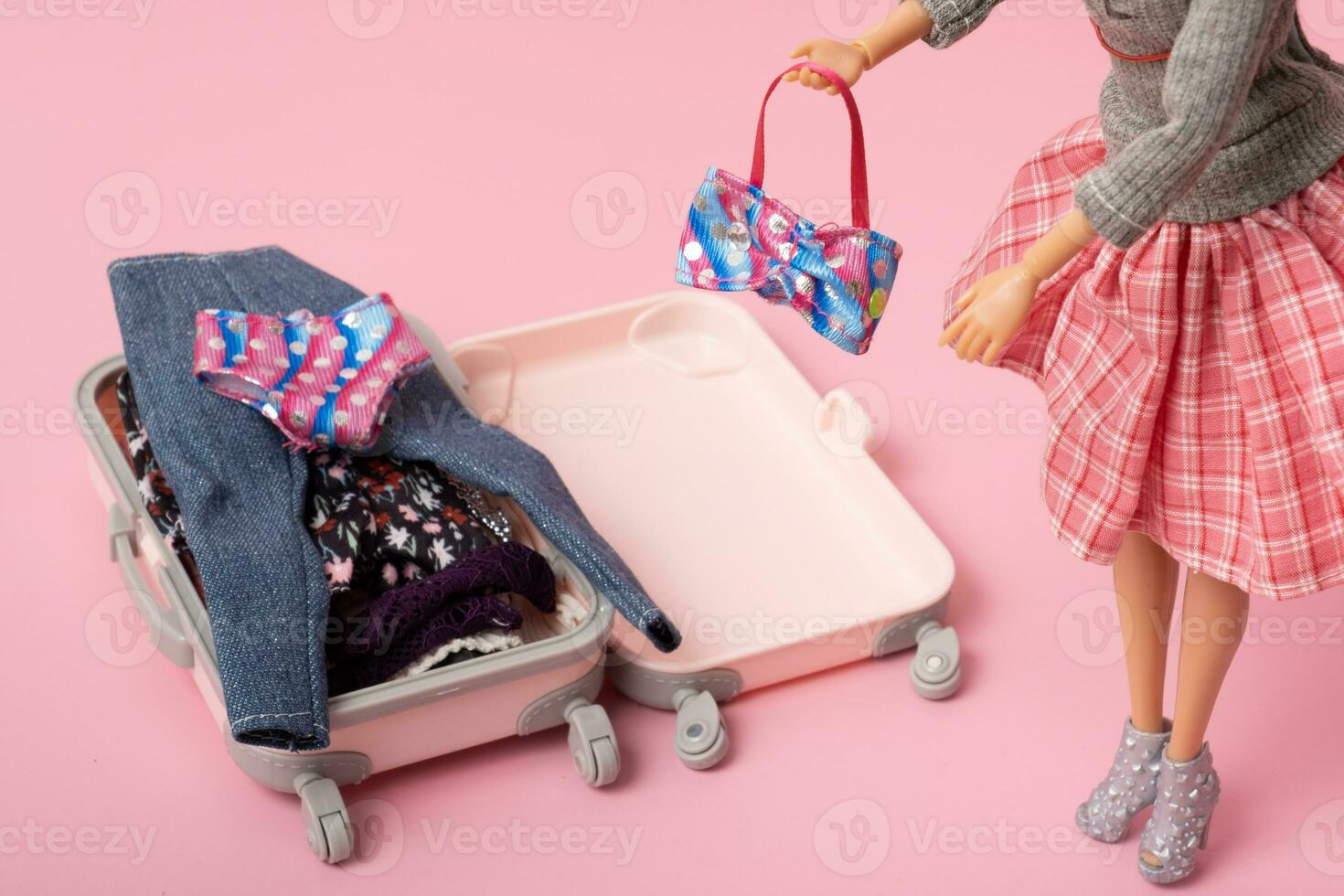 The doll puts swimsuit in a baggage. Preparing for traveling. Travel concept photo