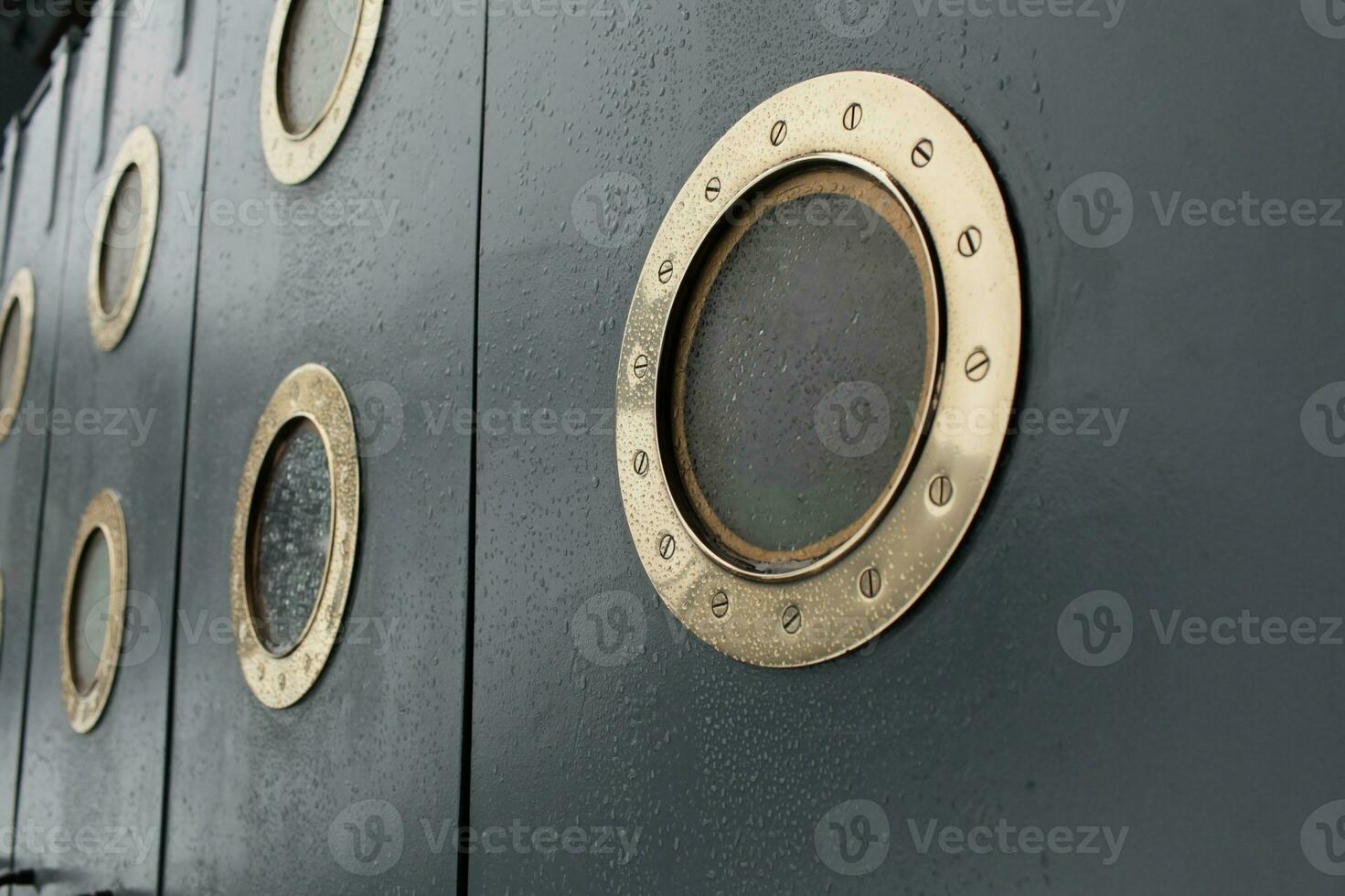 round portholes, shiny bronze, old ship, raindrops, water splashes, storm photo