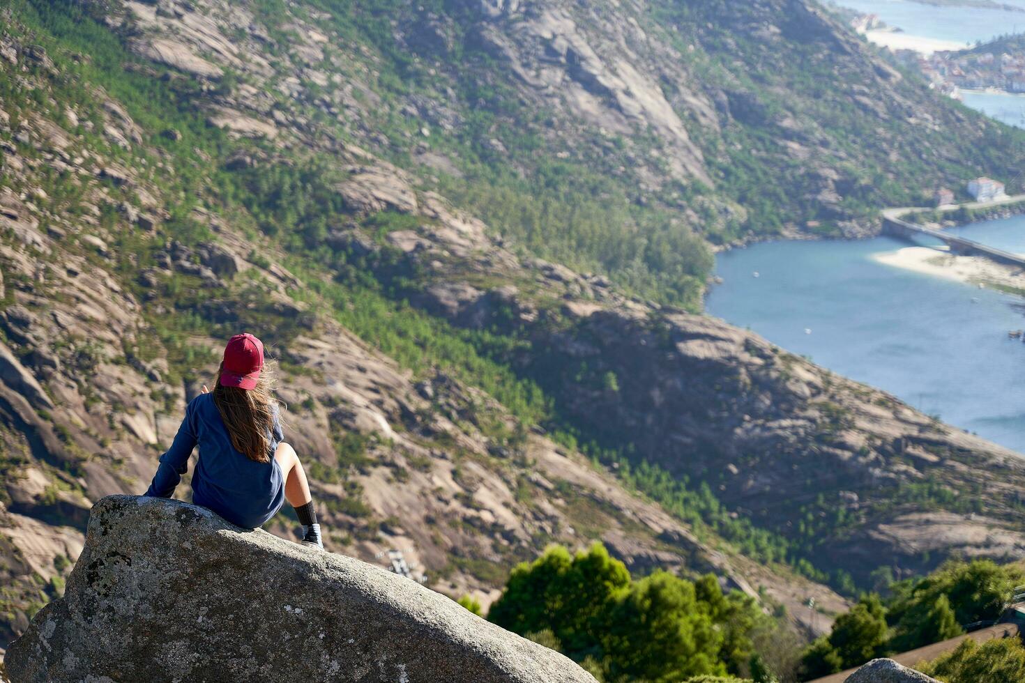 Girl with red cap is on a rock on the top of the mountain overlooking the Atlantic coast. photo