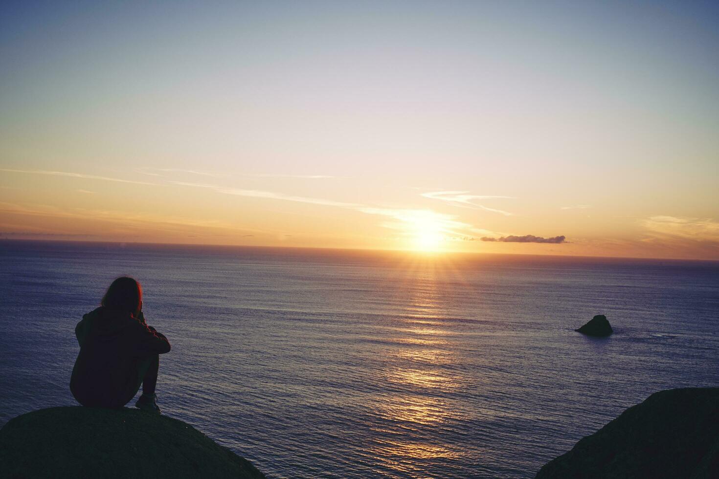 Young girl watching a sunset over the north sea photo