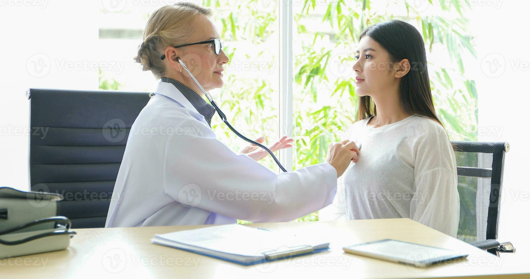Asian woman patient sitting with doctor about her illness and showing x-ray results with blood pressure and heart rate measurement with stethoscope photo