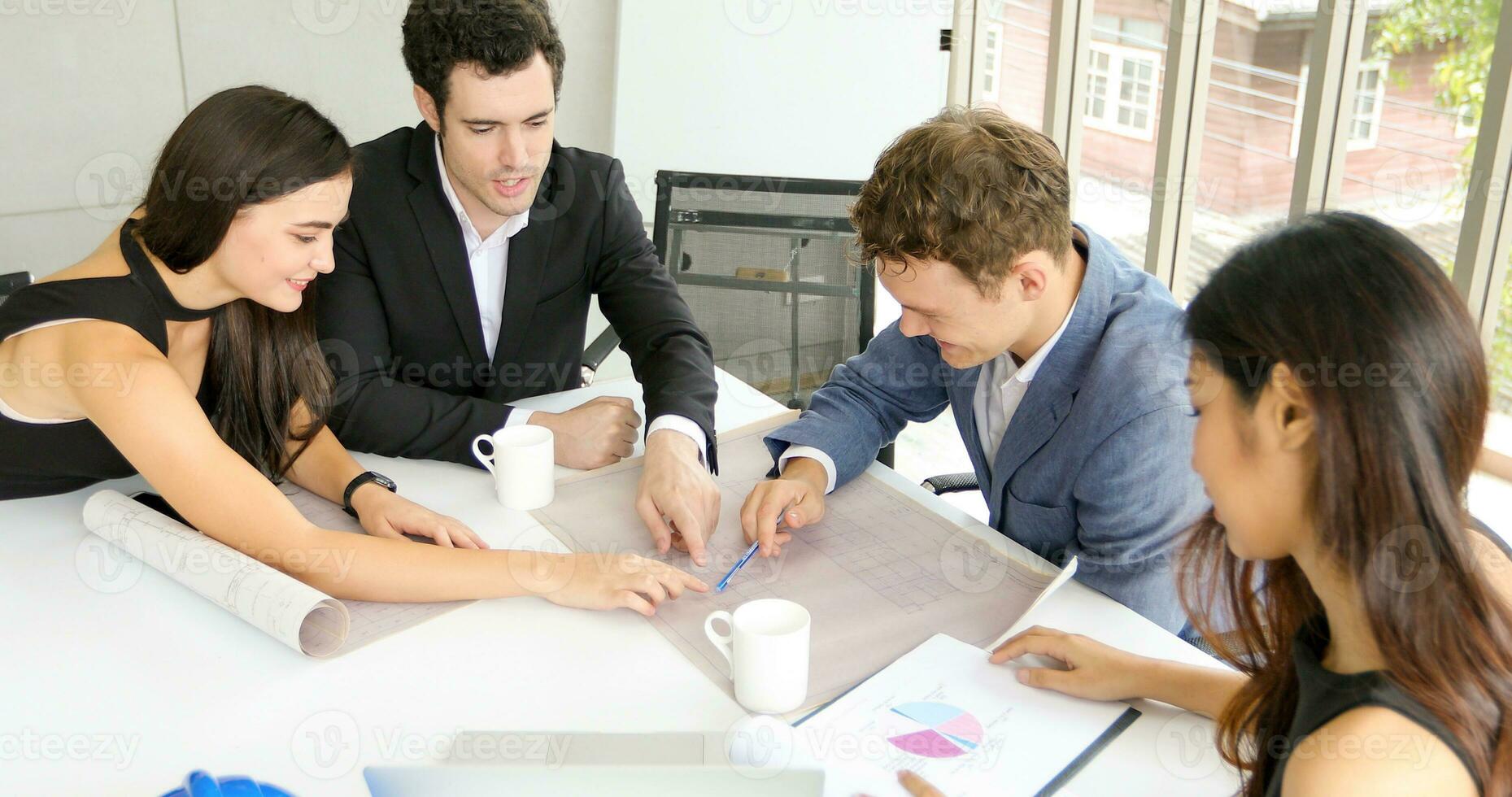 Diverse group of engineers, technicians, and specialists on meeting analyze technical drafts and hardhat presenting blueprint to business people in office photo