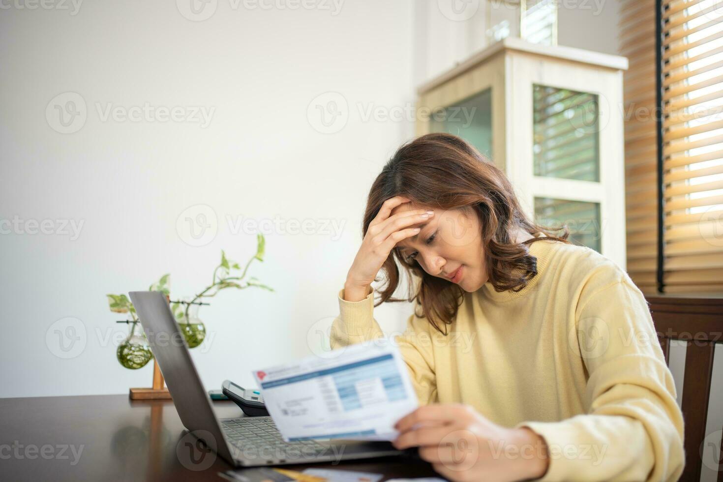 A woman uses a calculator to check the sum of her home expenses and she is stressed over the home expenses. photo