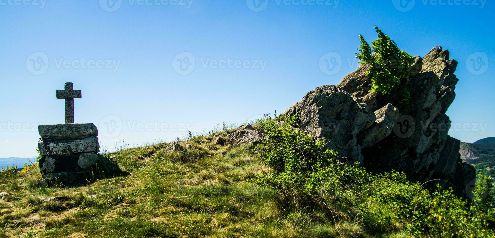 a cross on a hillside with a mountain in the background photo