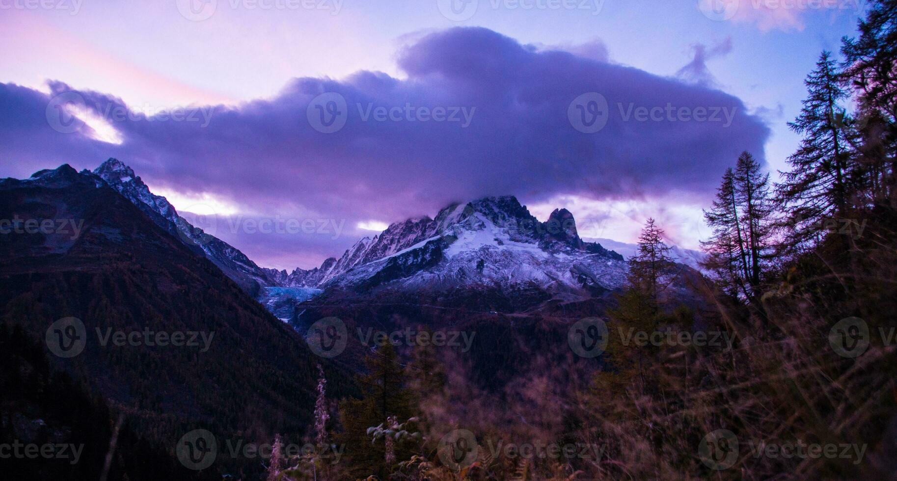 a lone tree stands in the middle of a mountain range photo