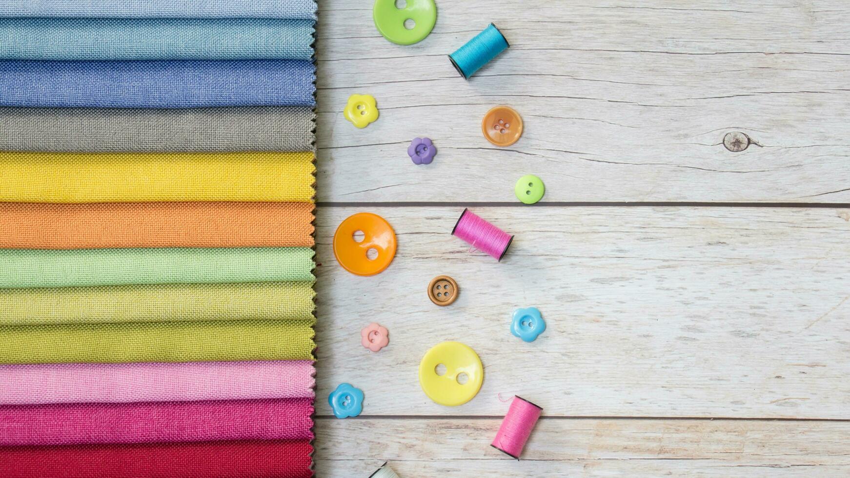 colorful fabric on wooden background with buttons and sewing thread photo