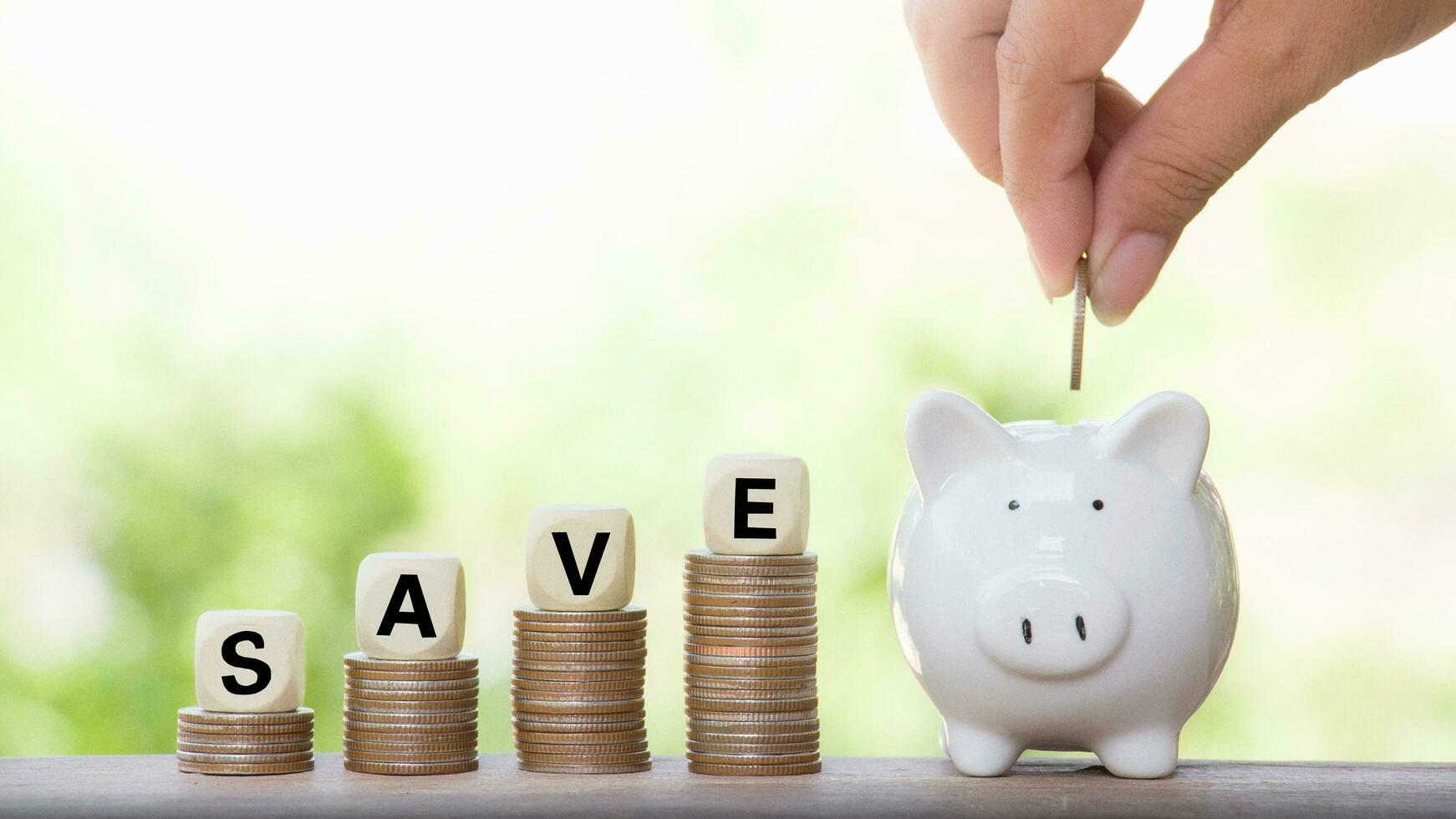 Close up of woman's hand putting coin into the piggy bank for saving concept photo