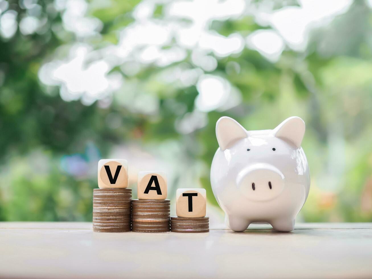 Piggy bank and Wooden blocks with the word VAT on stack of coins. The concept of save money for paying VAT in the future. photo