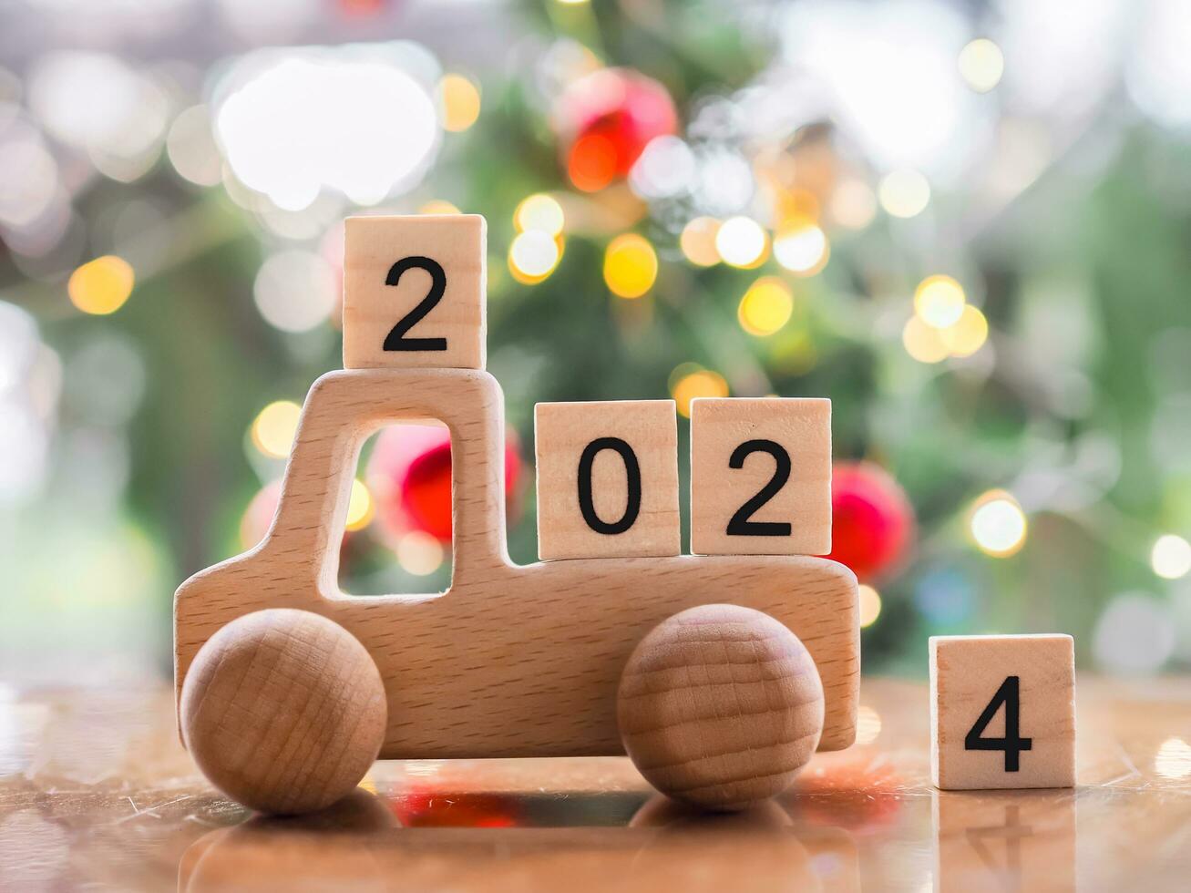 Wooden block number 2024 on wooden toy car with Christmas light bokeh background. Merry Christmas and Happy New Year, The concept of car in new year 2024. photo