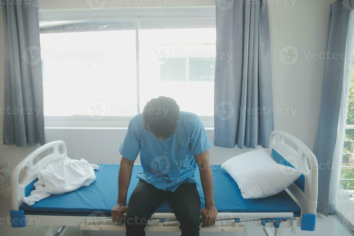 Depressed senior man sitting on the hospital bed alone at night, he feels lonely and abandoned photo
