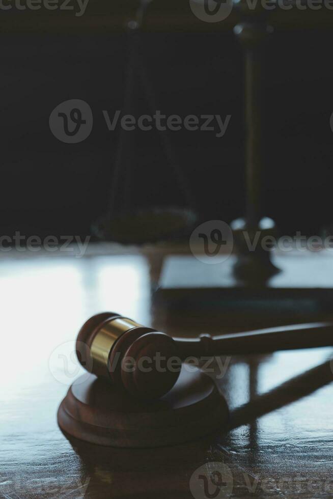 Justice and law concept.Male judge in a courtroom with the gavel, working with, computer and docking keyboard, eyeglasses, on table in morning light photo
