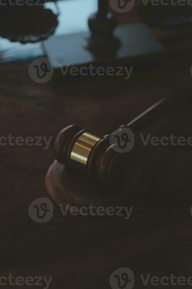 Justice and law concept.Male judge in a courtroom with the gavel, working with, computer and docking keyboard, eyeglasses, on table in morning light photo
