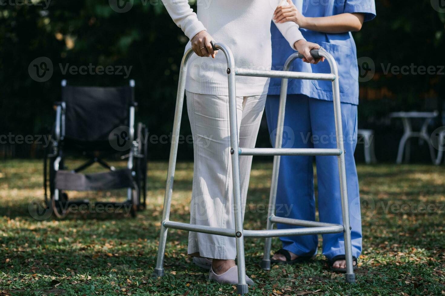 Asian young woman nurse at nursing home take care disabled senior man. Caregiver doctor serve physical therapy for older elderly patient to exercise and practice walking on walker or cane at backyard. photo