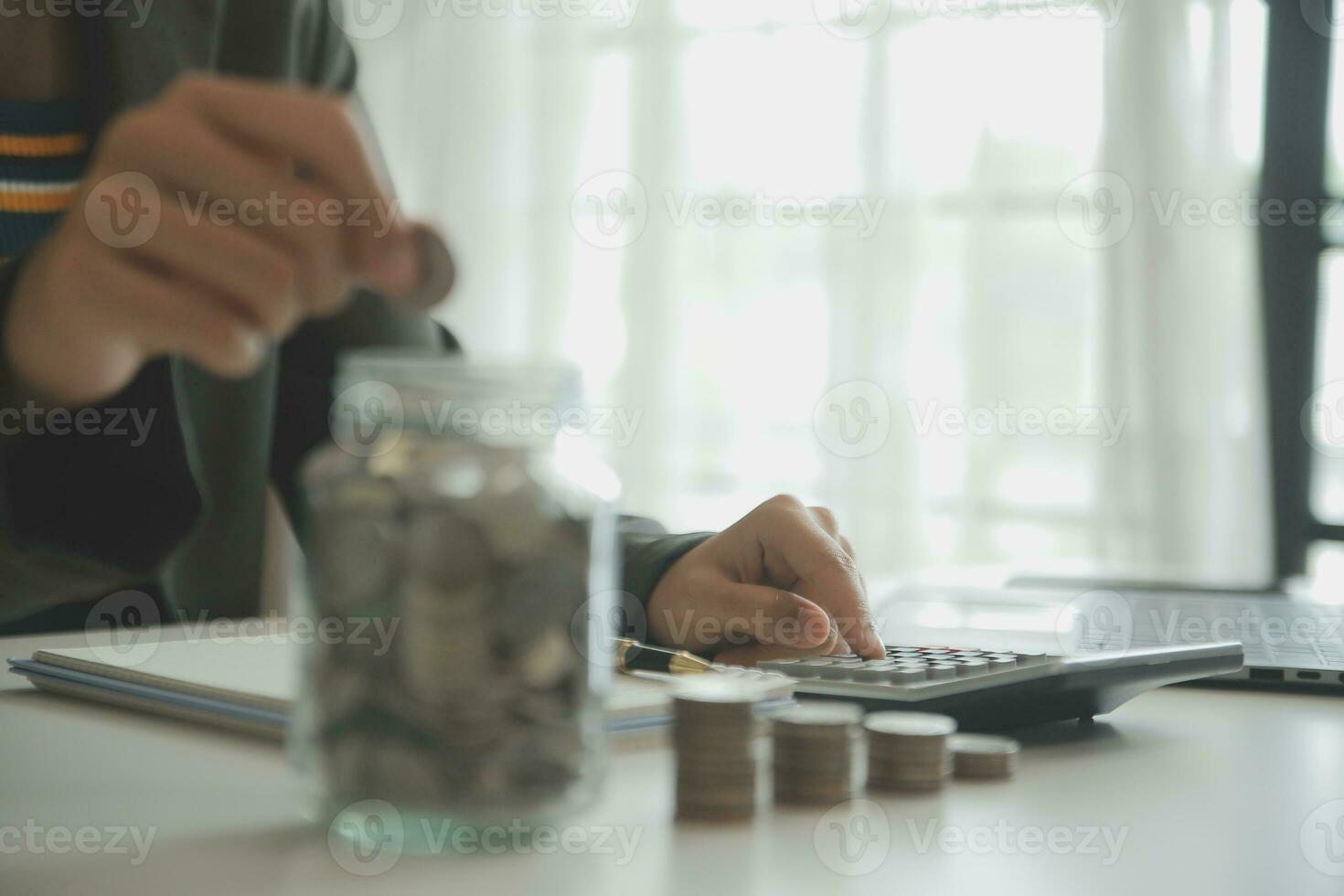 saving money and accounting concept. business man putting coin insert to jar and make acounting book for finance management to investment and saving. photo