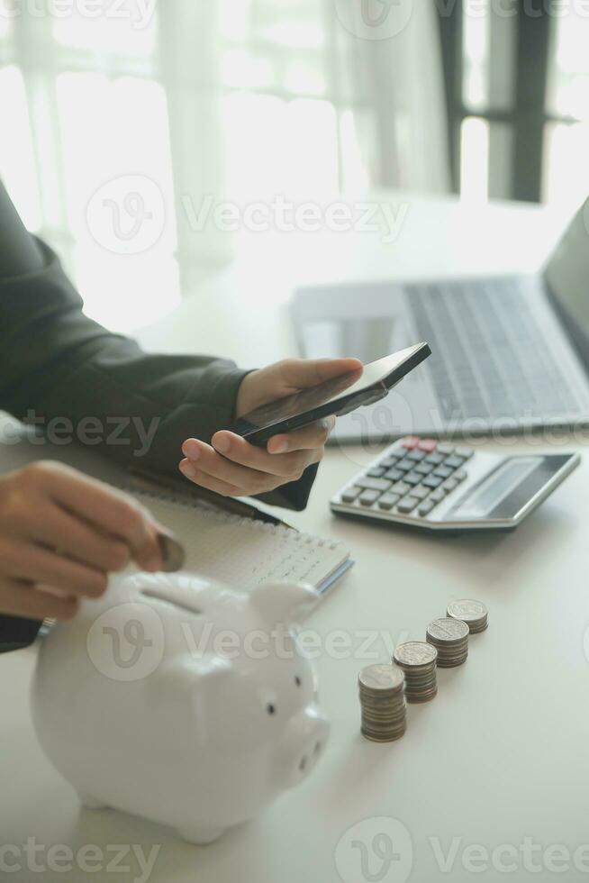 saving money and accounting concept. business man putting coin insert to jar and make acounting book for finance management to investment and saving. photo