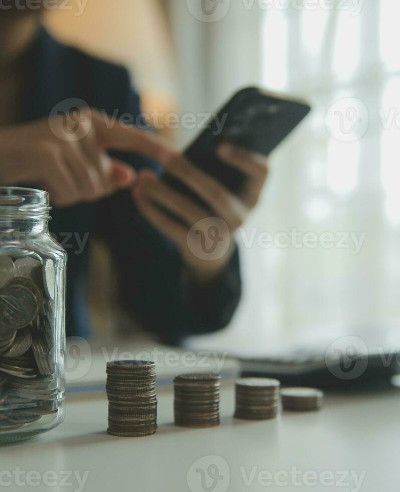 ahorro dinero y contabilidad concepto. negocio hombre poniendo moneda insertar a tarro y hacer contabilidad libro para Finanzas administración a inversión y ahorro. foto