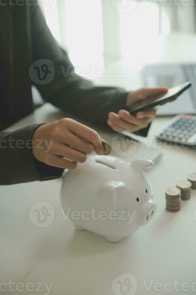 saving money and accounting concept. business man putting coin insert to jar and make acounting book for finance management to investment and saving. photo