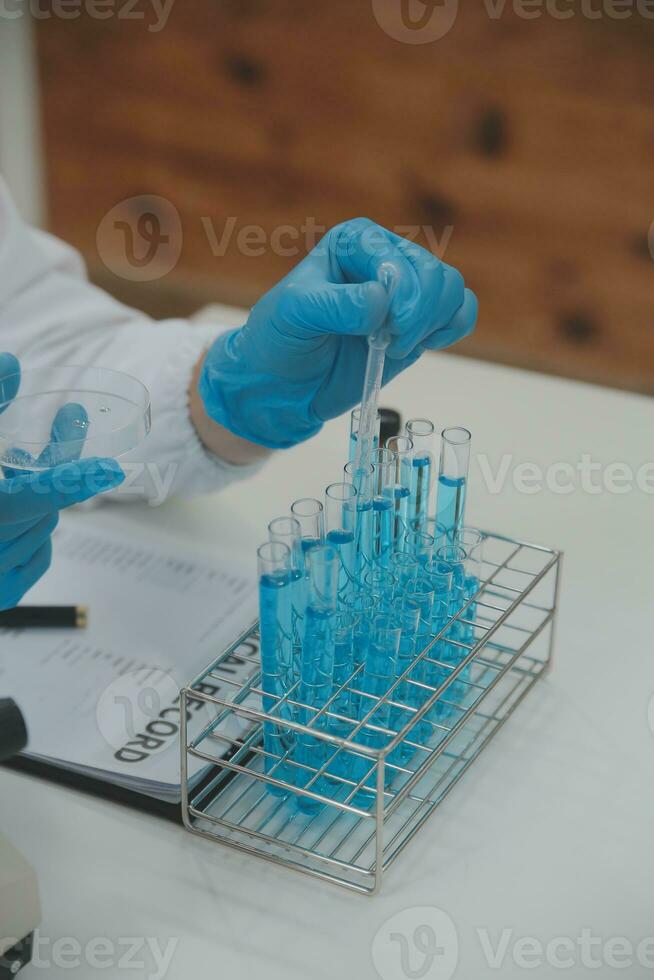 Scientist or medical in lab coat working in biotechnological laboratory, Microscope equipment for research with mixing reagents in glass flask in clinical laboratory. photo