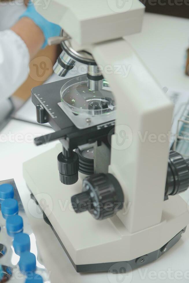 Scientist or medical in lab coat working in biotechnological laboratory, Microscope equipment for research with mixing reagents in glass flask in clinical laboratory. photo