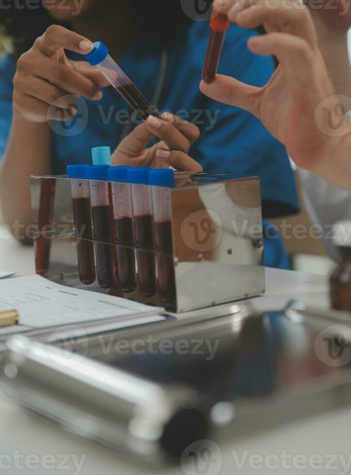 Medical worker in lab coat and sterile mask, doing a microscope analysis while her colleague are working behind photo