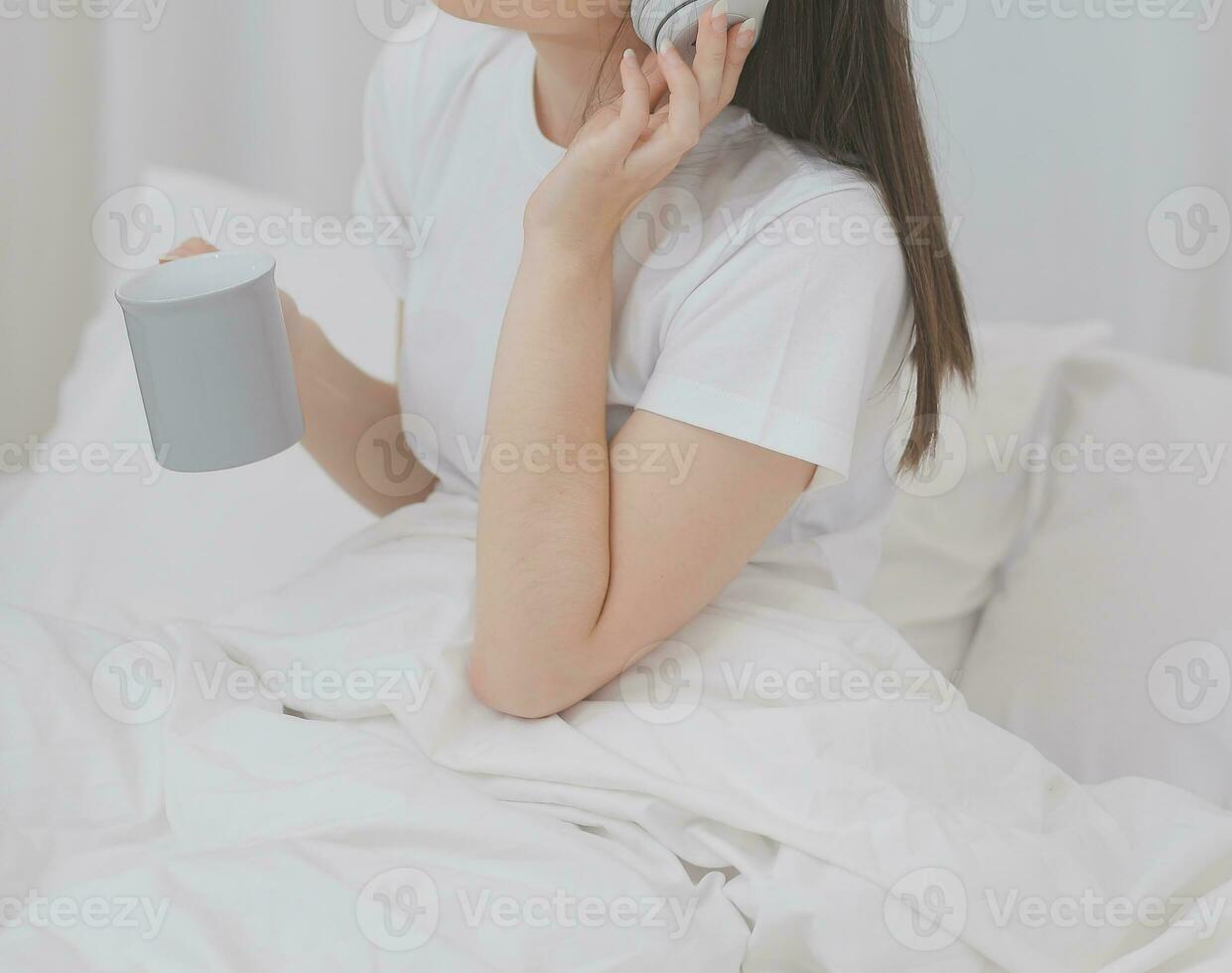 eficiente joven milenario niña sentado en un cama en el mañana, usos ordenador portátil computadora y come croissants y bebidas café para desayuno foto
