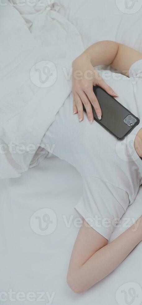 Efficient Young Millennial Girl Sitting on a Bed in the Morning, Uses Laptop Computer and Eats Croissants and Drinks Coffee for Breakfast photo