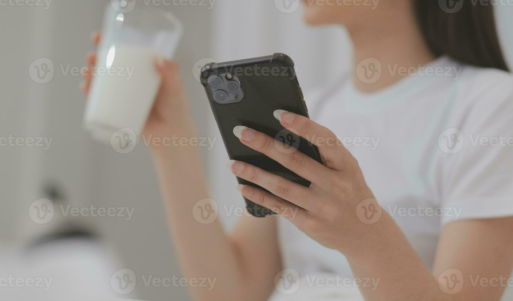 Efficient Young Millennial Girl Sitting on a Bed in the Morning, Uses Laptop Computer and Eats Croissants and Drinks Coffee for Breakfast photo