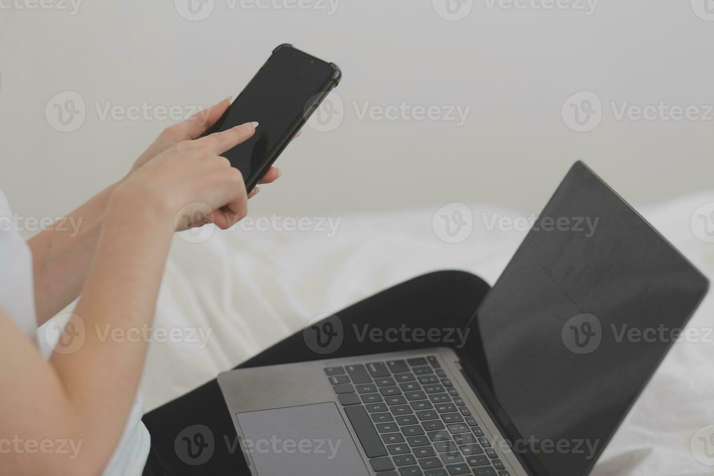 Efficient Young Millennial Girl Sitting on a Bed in the Morning, Uses Laptop Computer and Eats Croissants and Drinks Coffee for Breakfast photo