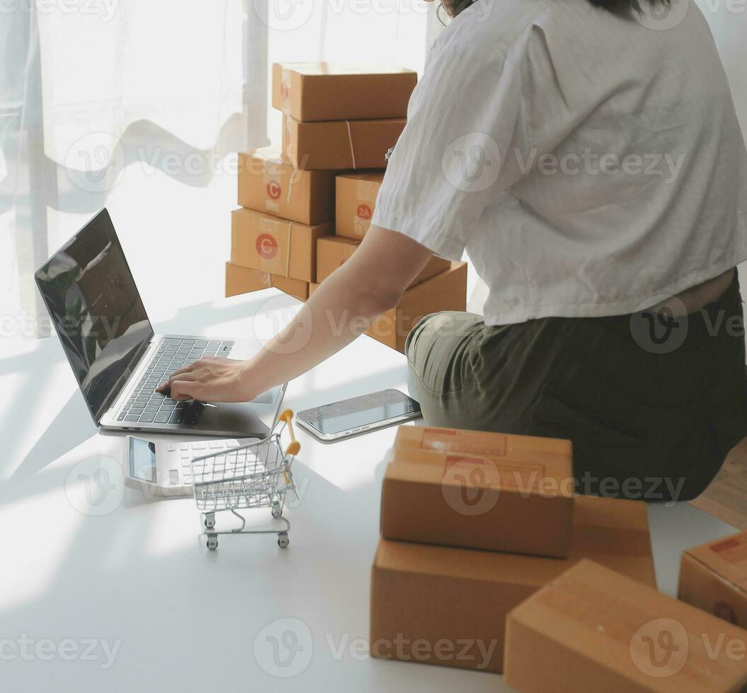 Portrait young attractive hipster asia female owner startup look at camera work happy with box at home prepare parcel delivery in sme supply chain, procurement, omnichannel ecommerce online concept. photo