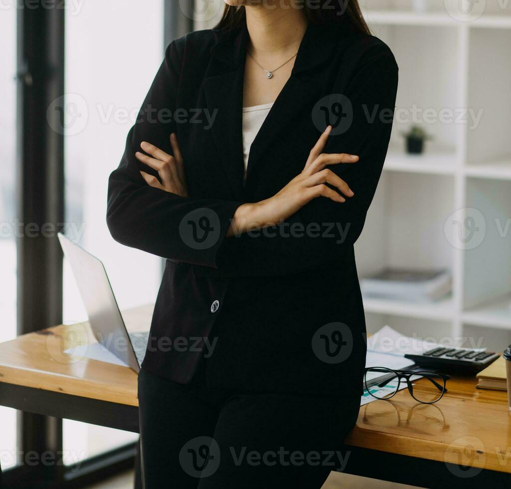 Asian Businesswoman Using laptop computer and working at office with calculator document on desk, doing planning analyzing the financial report, business plan investment, finance analysis concept. photo