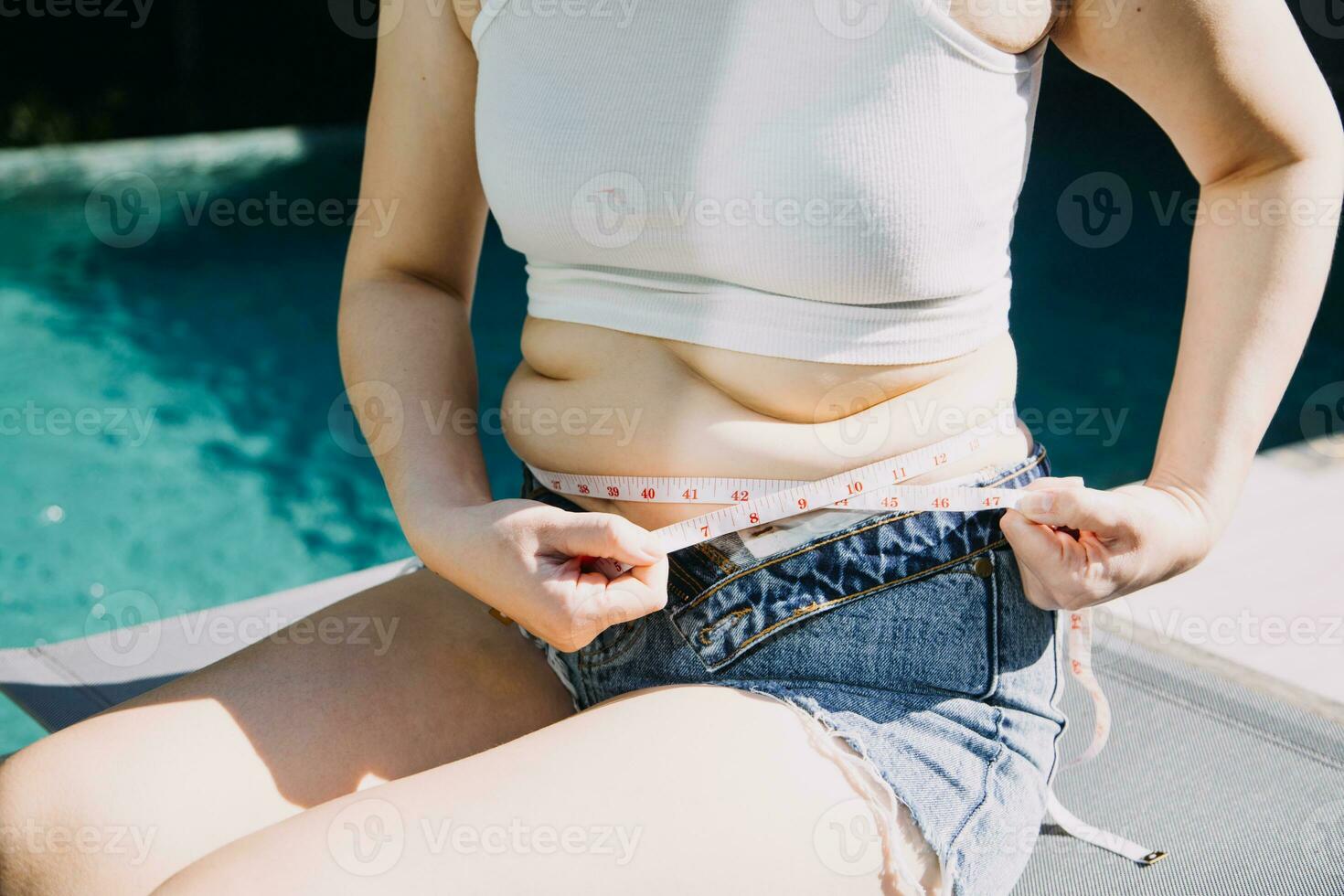 mujer gorda, barriga gorda, gordita, mujer obesa mano sosteniendo grasa abdominal excesiva con cinta métrica, concepto de estilo de vida de dieta de mujer foto