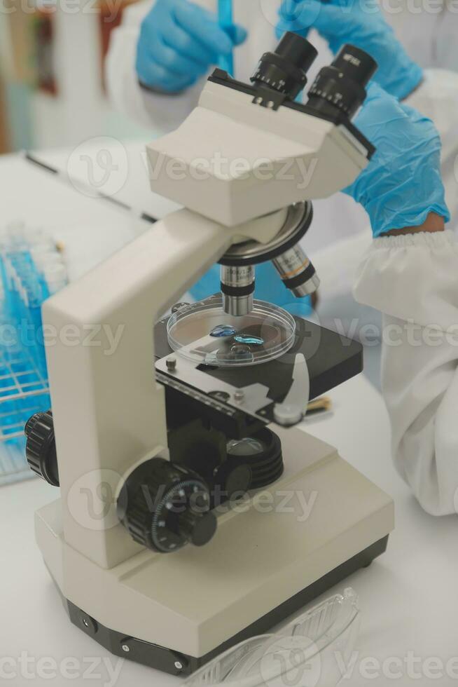 Health care researchers working in life science laboratory. Young female research scientist and senior male supervisor preparing and analyzing microscope slides in research lab. photo